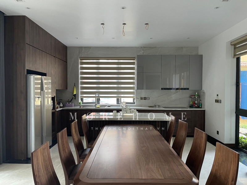 Tủ bếp chữ L gỗ tự nhiên có mặt đá vuông và 2 cánh mở ra, giúp triệt để các góc chết, tạo cảm giác thoáng đãng và tiện lợi trong sử dụng.